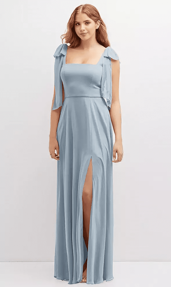 Model wearing a dusty blue square-neck bridesmaid dress with draped cape sleeves and a front slit at Lakeside Bridal in Traverse City, Michigan.